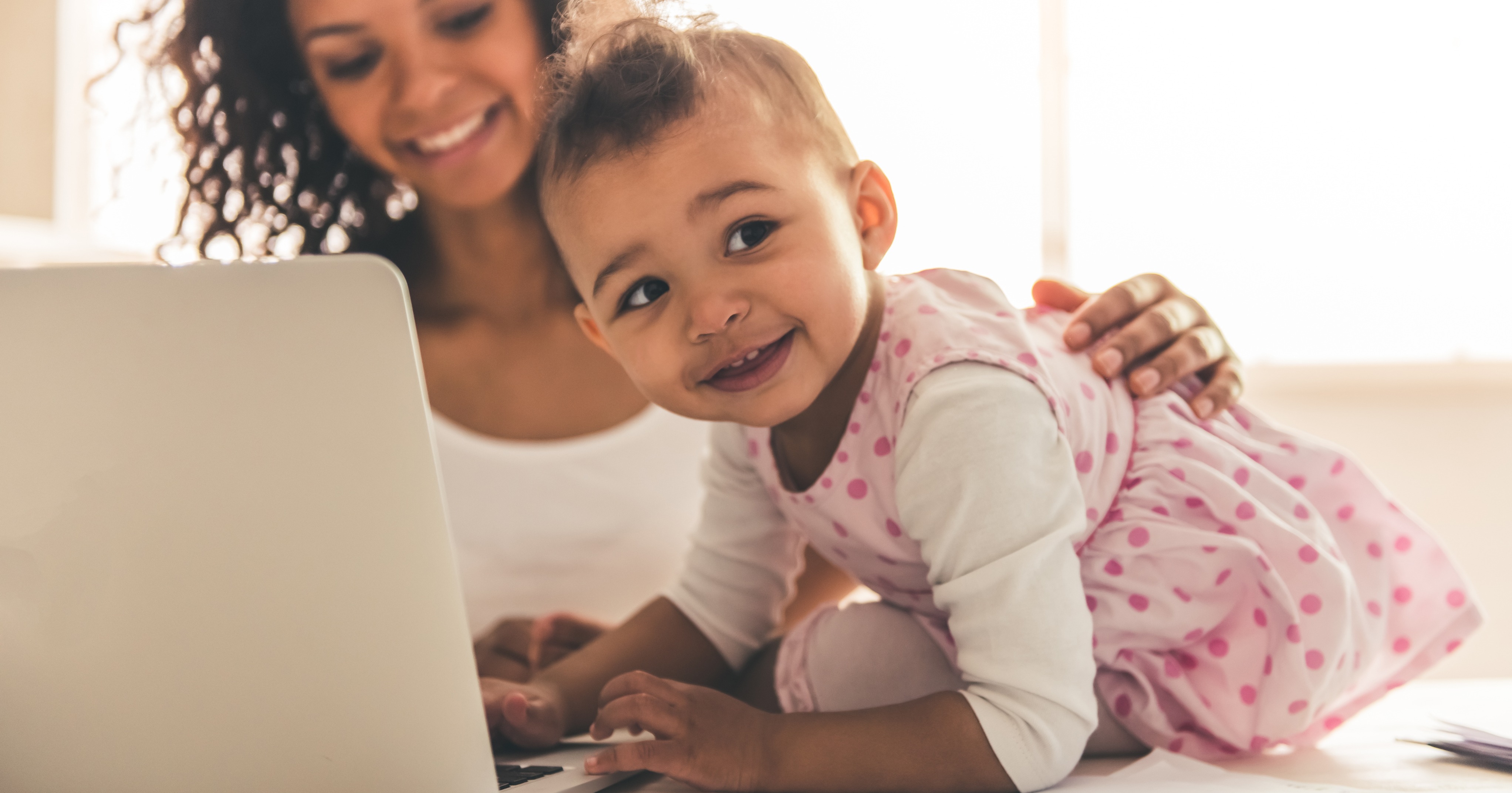 mother and baby smiling in front of a laptop